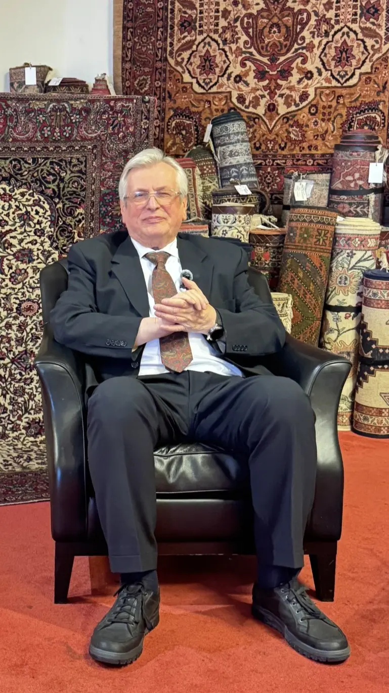 Rudolf Koppensteiner sitzend umgeben von Orientteppichen